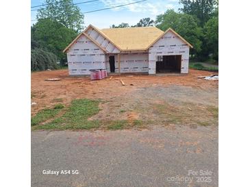 New construction home showing exterior with visible framing and the beginning stages of the roof install at 302 W Second St, Lowell, NC 28098