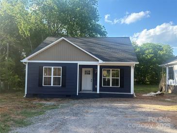 Charming single-story home featuring navy siding, a white front door, black shutters, and a well-manicured lawn at 630 W Bell St, Statesville, NC 28677