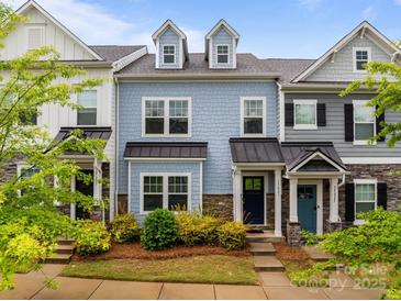 Charming townhome featuring blue siding, stone accents, dormer windows, and manicured landscaping in a well-maintained community at 15021 Meacham Farm Dr, Huntersville, NC 28078
