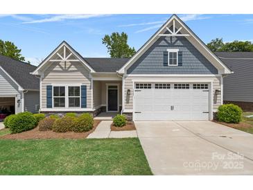Charming home featuring a two-car garage, manicured lawn, and stylish architectural details under a bright blue sky at 1747 Slippery Rock Ln, Monroe, NC 28112
