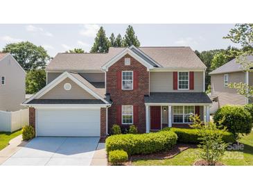 Traditional two-story home featuring red shutters, brick accents, a two-car garage, and manicured landscaping at 10815 Mountain Springs Dr, Charlotte, NC 28278