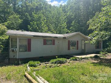 Cottage-style home with red shutters nestled among mature trees offers an inviting natural setting at 156 Hurst Dr, Statesville, NC 28677