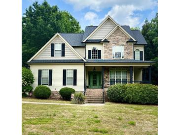 Inviting two-story home with a covered front porch, stone accents, manicured landscaping, and a vibrant green front door at 3320 Harvey Ln, Monroe, NC 28110