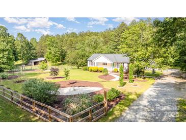 Beautifully landscaped yard with charming home, wooden fence and mature trees at 120 Mossy Rock Trl, Iron Station, NC 28080