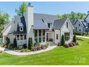 Stunning two-story home featuring a modern design with a metal roof, white brick and a perfectly manicured front lawn at 14228 Ryker Way, Davidson, NC 28036
