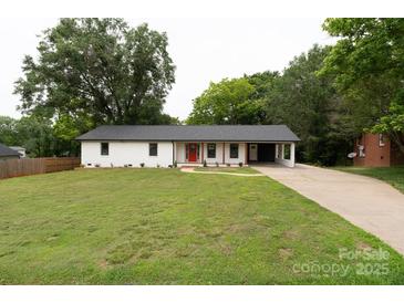 Charming single-story home featuring a vibrant red front door, a well-manicured lawn, and a convenient attached carport at 1537 Spangler Dr, Shelby, NC 28150
