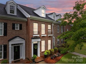 Charming brick townhome featuring manicured landscaping, dormer windows and covered front entry at 16930 Summers Walk Blvd, Davidson, NC 28036