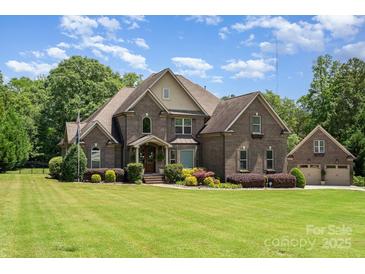 Beautiful brick home featuring manicured lawn and a three car garage on a sunny day at 5183 Mill Race Ln, Lancaster, SC 29720
