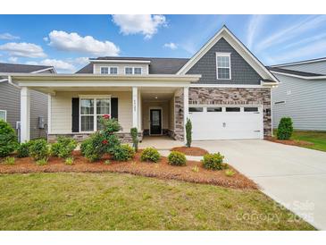 Charming home featuring a manicured lawn, stone accents, and a welcoming front porch at 5723 Notch Peak Ave, Indian Land, SC 29707