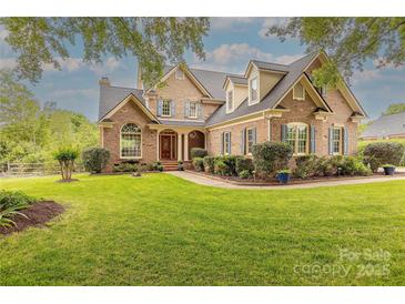 Elegant brick home featuring a lush lawn, blue shutters, mature landscaping, and welcoming front entrance at 6024 Highview Rd, Weddington, NC 28104