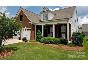 Charming brick home with a covered front porch, well-maintained lawn, and two-car garage at 6310 Highland Commons Rd, Charlotte, NC 28269