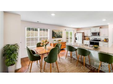 Bright dining area features a wooden table with six green chairs, a sideboard, and a large window at 7205 Finnigan Rd, Charlotte, NC 28215