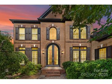Elegant brick home featuring an arched doorway, complemented by dark shutters and manicured landscaping at 9625 Donna Ve Ln, Charlotte, NC 28277