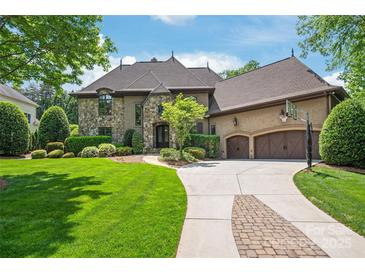 Stone and stucco exterior with a manicured lawn and three-car garage on a sunny day at 18843 Flat Shoals Dr, Cornelius, NC 28031