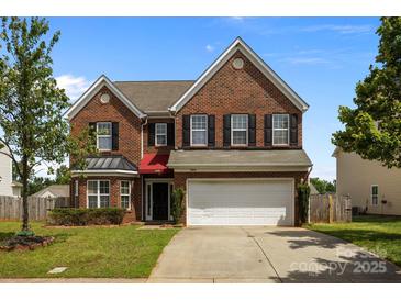 Charming two-story brick home with a well-manicured lawn, a two-car garage, and black shutters at 2018 Rockycreek Ln, Monroe, NC 28112