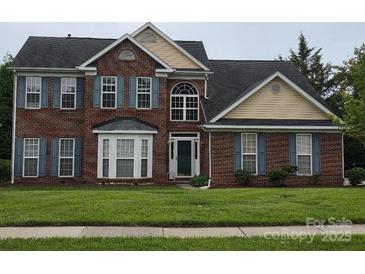 Charming two-story brick home featuring blue shutters, a well-manicured lawn, and a classic architectural design at 6017 Lowergate Dr, Waxhaw, NC 28173