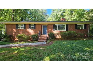 Charming brick ranch home with a blue door and well-maintained landscaping, surrounded by mature trees at 7021 Linda Lake Dr, Charlotte, NC 28215