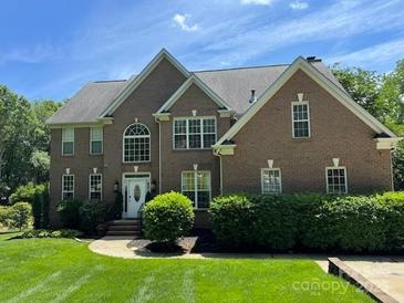 Charming brick home with arched window, manicured lawn, and mature landscaping at 706 Evans Manor Dr, Matthews, NC 28104