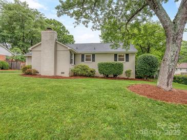 Charming single story home featuring a brick chimney, lush lawn, and mature trees for added curb appeal at 1227 Seneca Pl, Charlotte, NC 28210