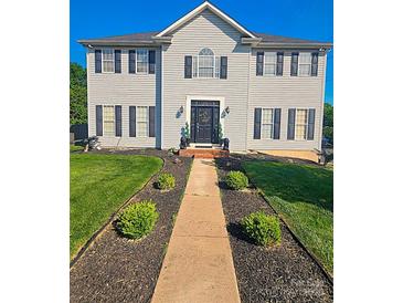Traditional two-story home featuring manicured lawn and beautiful walkway leading to the front door at 12304 Sandringham Pl, Charlotte, NC 28262