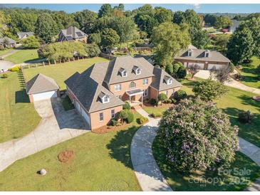 Expansive brick home showcasing meticulously manicured landscaping, mature trees, and a circular driveway at 150 Northchase Dr, Concord, NC 28027