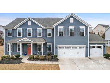 Charming two-story home showcasing a blue exterior, red door, manicured landscaping, and an attached two-car garage at 1620 Callahan Rd, Fort Mill, SC 29715
