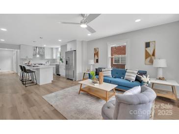 Bright open-plan living room with a modern kitchen, blue sofa, light wood floors and minimalist decor at 1829 Jennings St, Charlotte, NC 28216