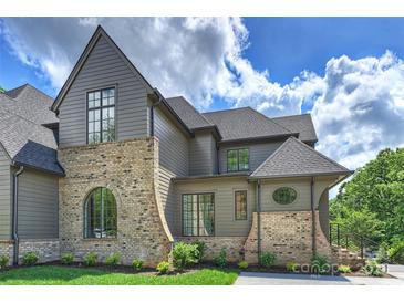 View of the house with a gray exterior, brick details, and multiple windows, set against a partly cloudy sky at 536 Hillside Ave, Charlotte, NC 28209