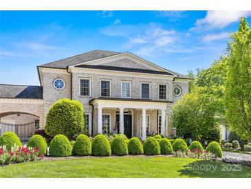 Elegant brick home featuring a columned front porch, manicured lawn and mature landscaping at 5917 Saint John Ln, Charlotte, NC 28210