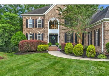 Beautiful brick home featuring a manicured lawn, lush landscaping, and a welcoming front entrance at 7501 Cleyera Cir, Waxhaw, NC 28173
