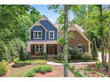 Charming two-story home featuring a mix of brick and blue siding, a welcoming porch, and lush landscaping at 1328 Huntcliff Dr, Waxhaw, NC 28173