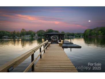 Lake house dock featuring bench seating and boat slip with picturesque views during sunset at 230 Shady Cove Rd, Troutman, NC 28166