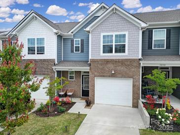 Charming townhome with brick accents, a one-car garage, and a beautifully landscaped front yard at 5034 Moss Pine Way, Tega Cay, SC 29708