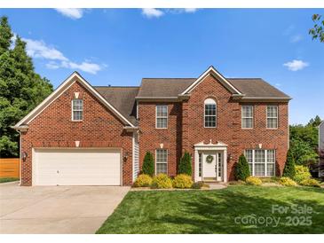 Charming two-story red brick home with a well-manicured lawn and beautiful landscaping at 611 Meadow Lake Dr, Matthews, NC 28105