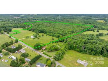 Expansive aerial view showcases a vast property with lush greenery and a mix of open fields and wooded areas at 9161 Paul Payne Store Rd, Stony Point, NC 28678