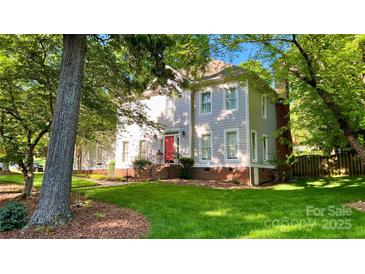 Charming two-story home with a red front door, lush lawn, and mature trees surrounding the property at 10338 Hollybrook Dr, Charlotte, NC 28277