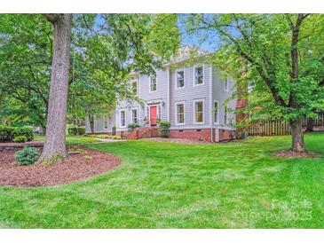 Charming two-story home featuring a well-manicured lawn and vibrant green trees on a sunny day at 10338 Hollybrook Dr, Charlotte, NC 28277