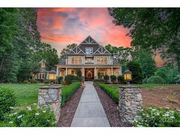 Beautiful home exterior featuring a manicured lawn, inviting front porch, and professionally landscaped walkway at 157 Dedham Loop, Mooresville, NC 28117