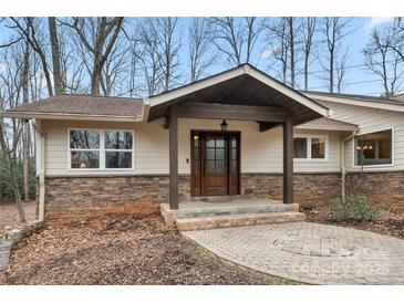 Charming home entrance featuring a stone facade, covered porch, and a beautiful dark wood front door with decorative glass at 64 Timberidge Dr, Lake Wylie, SC 29710