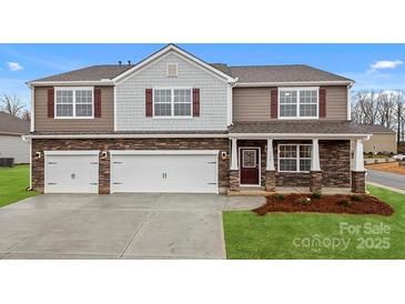 Beautiful two-story home with a three car garage, brick accents, lush lawn, and a covered porch at 8025 Kennesaw Dr, Gastonia, NC 28056