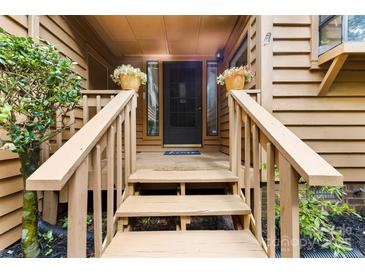 Inviting entryway with warm wood steps, flower pots, and a welcoming blue 'Home' doormat at 9013 St Croix Ln, Charlotte, NC 28277