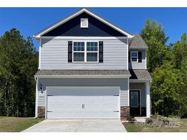 Two-story home with gray siding, black shutters, white garage door, and stone accents, creating a welcoming curb appeal at 1055 Mordred St, Richburg, SC 29729