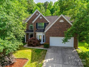 Charming brick home featuring a well-manicured lawn and a two-car garage, nestled among lush green trees at 12719 Vantage Point Ln, Huntersville, NC 28078