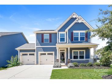 Charming two-story blue home features a manicured lawn, a two car garage, and covered porch at 2327 Glenway Trail Ct, Pineville, NC 28134