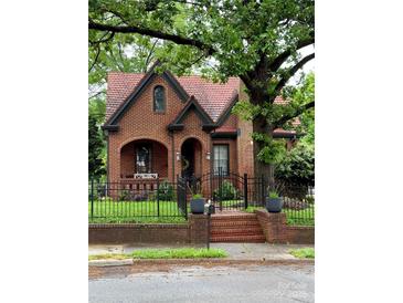 Charming brick home with a unique roof, arched entryway, black iron fence, and lush landscaping at 324 N 5Th St, Albemarle, NC 28001