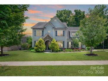 Charming two-story home with a manicured lawn, mature trees, and stone accents around the entrance at 4225 Abernathy Pl, Harrisburg, NC 28075