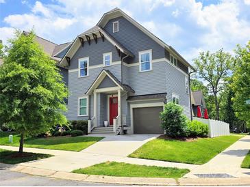 Charming two-story home features a gray exterior, red front door, attached garage and well-manicured lawn at 5210 Kelly St, Charlotte, NC 28205
