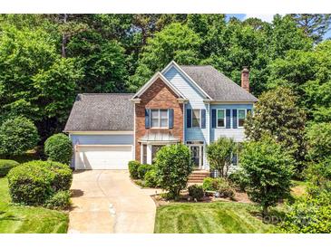 Charming two-story home with a lush lawn, mature trees, brick and blue siding, and an attached two-car garage at 5238 Downing Creek Dr, Charlotte, NC 28269