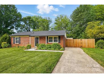 Charming brick home featuring a well-manicured lawn, mature trees, and a private driveway at 529 Dedmon Dr, Charlotte, NC 28216