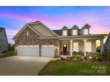 Charming single-Gathering home showcasing a stone facade, two-car garage, and inviting front porch area at dusk at 7010 Brush Crk, Monroe, NC 28110